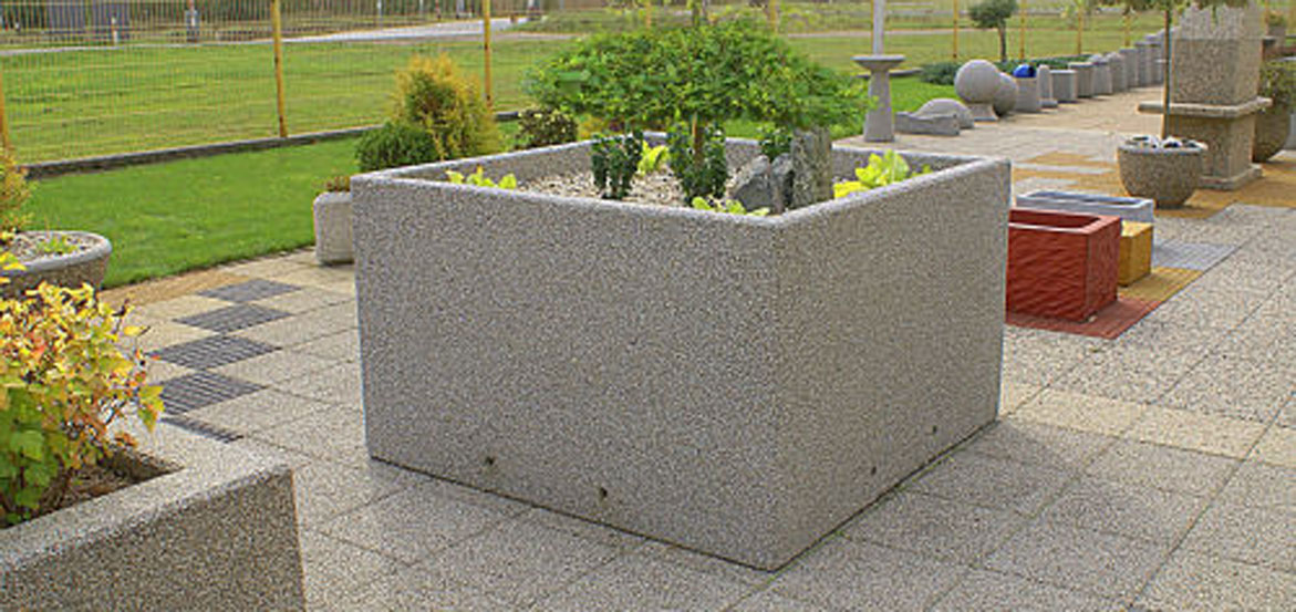 Duża kwadratowa donica wykonana w technologii betonu płukanego.