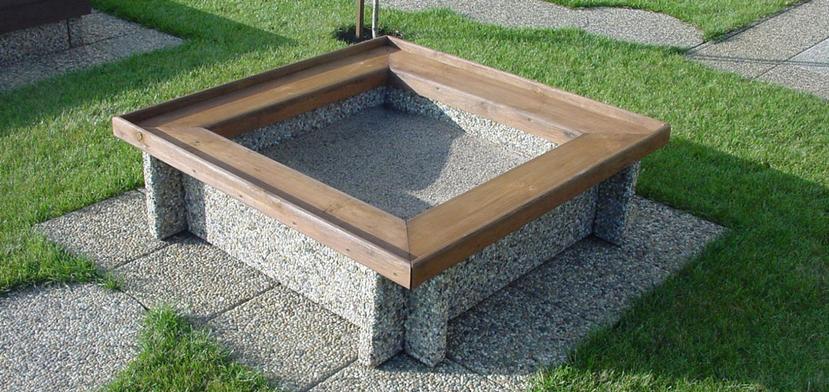 KR-116 to piaskownica wykonana w technologii betonu płukanego, wyposażona w drewniane siedzisko.