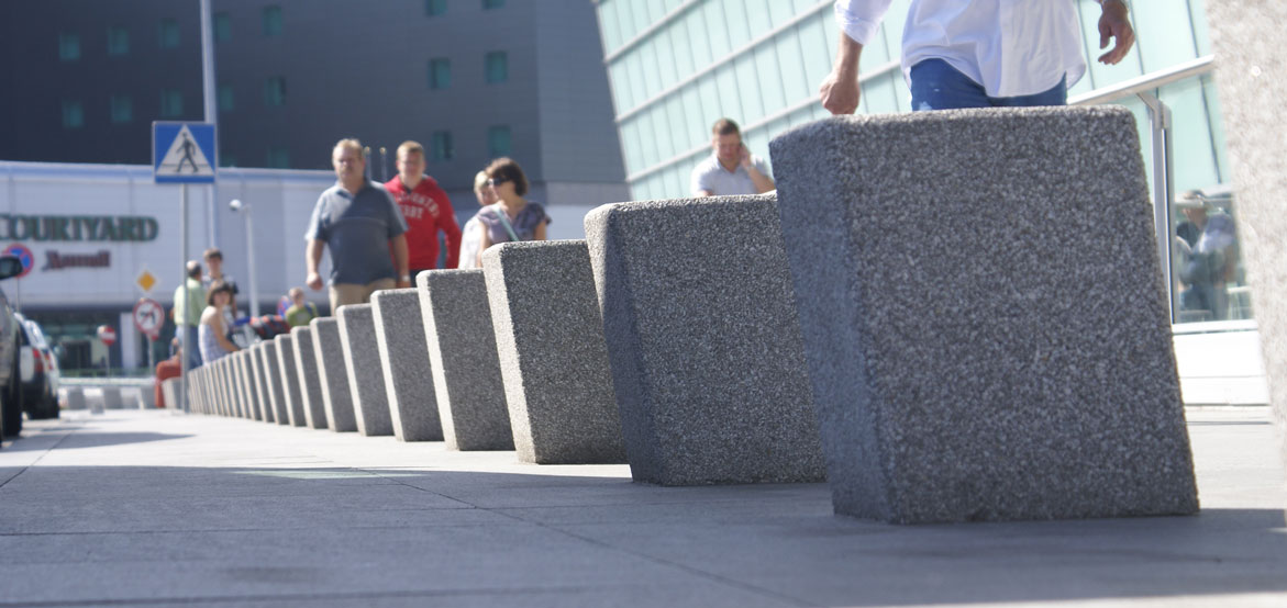 Betonowy pal parkingowy w kształcie pochylonego graniastosłupa wykonany w technologii betonu płukanego.